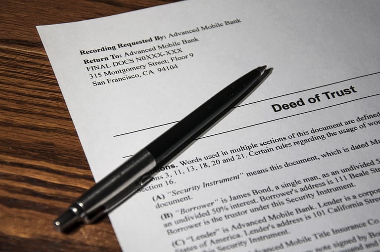 Close-up of a Deed of Trust document with a pen on top, highlighting key details for Advanced Mobile Bank.